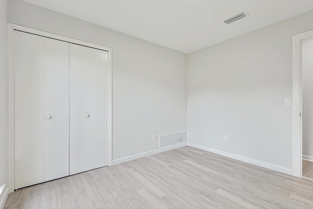 unfurnished bedroom with light hardwood / wood-style flooring and a closet