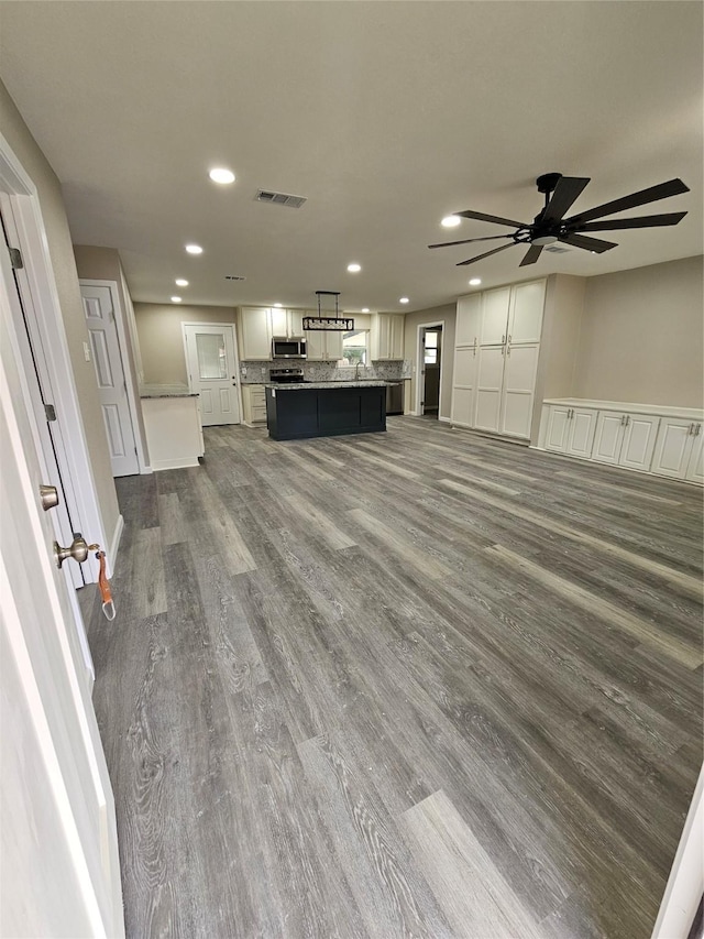 unfurnished living room featuring ceiling fan and dark hardwood / wood-style flooring