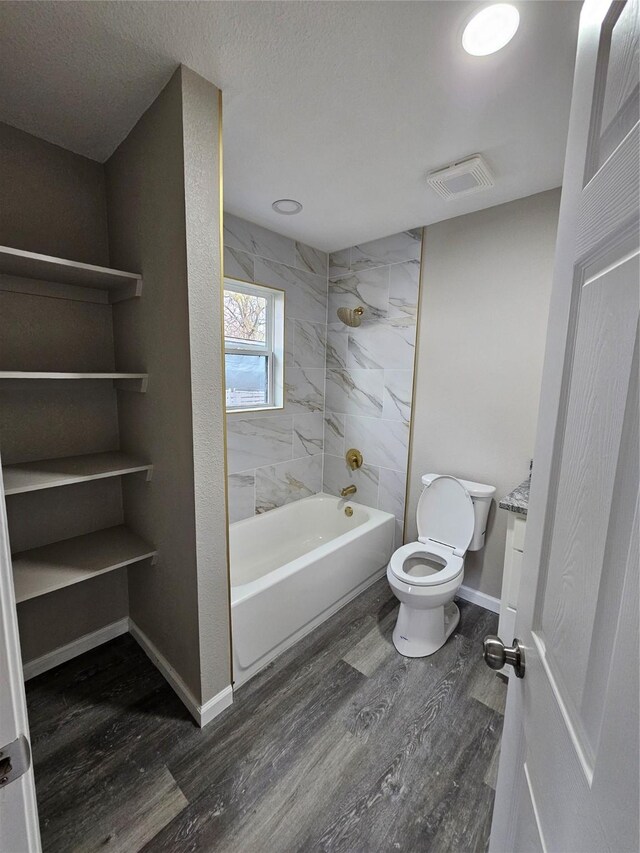 bathroom featuring hardwood / wood-style flooring, toilet, and tiled shower / bath