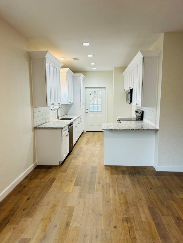 kitchen featuring stainless steel appliances, white cabinetry, light stone countertops, and sink