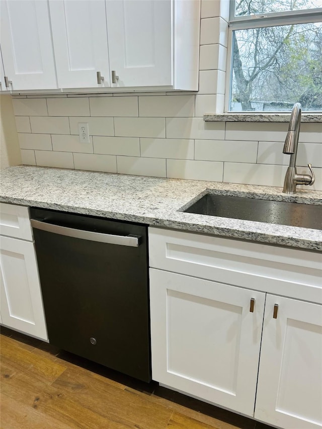 kitchen with white cabinetry, sink, decorative backsplash, and black dishwasher