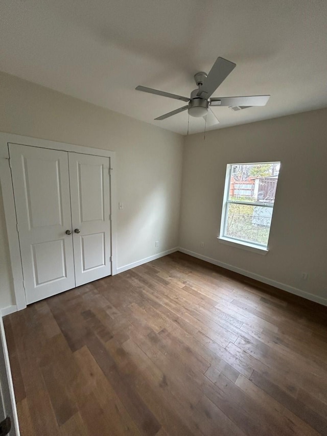 unfurnished bedroom featuring dark wood-type flooring, ceiling fan, and a closet