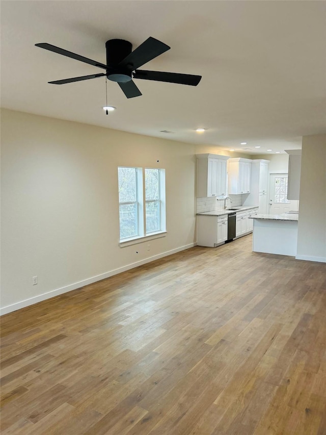 unfurnished living room featuring ceiling fan, sink, and light wood-type flooring