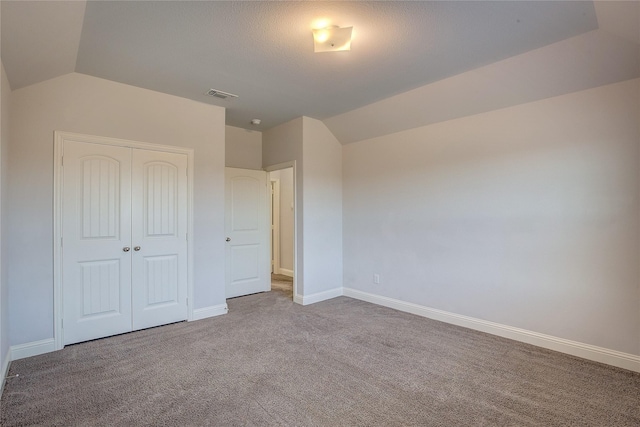 unfurnished bedroom featuring lofted ceiling, carpet floors, and a closet