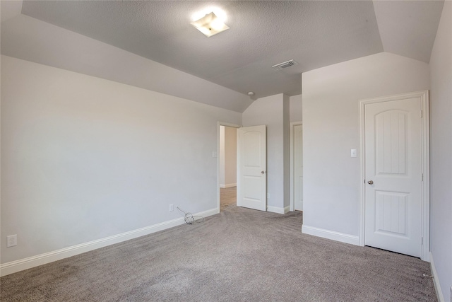 carpeted empty room with lofted ceiling and a textured ceiling