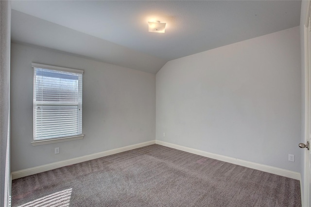 carpeted spare room with vaulted ceiling