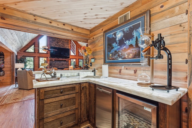 interior space featuring kitchen peninsula, wood ceiling, wooden walls, hardwood / wood-style floors, and wine cooler