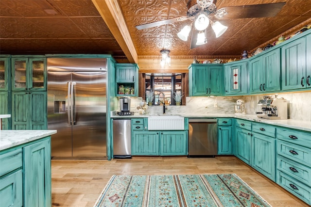 kitchen featuring light stone countertops, stainless steel appliances, ceiling fan, sink, and light hardwood / wood-style flooring