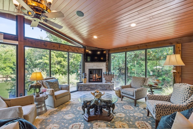 living room featuring a stone fireplace, ceiling fan, plenty of natural light, and wood ceiling