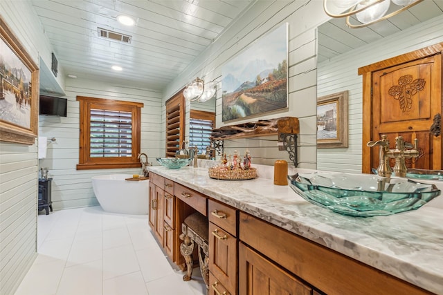 bathroom with wooden walls, tile patterned flooring, vanity, and a bath