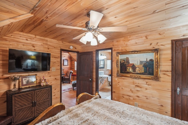 bedroom with ensuite bath, ceiling fan, wooden walls, and wood-type flooring