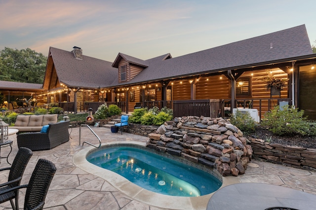 pool at dusk featuring outdoor lounge area, a patio, and a hot tub