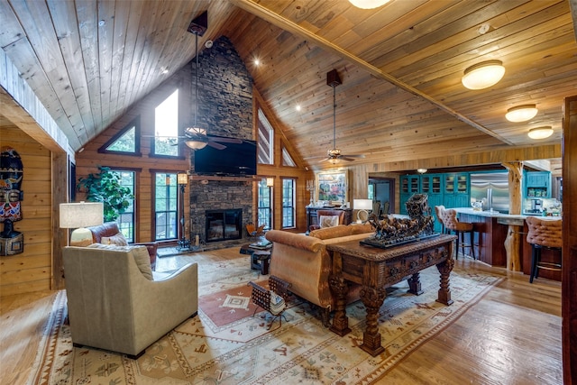 living room with wood ceiling, wood walls, ceiling fan, and light hardwood / wood-style floors