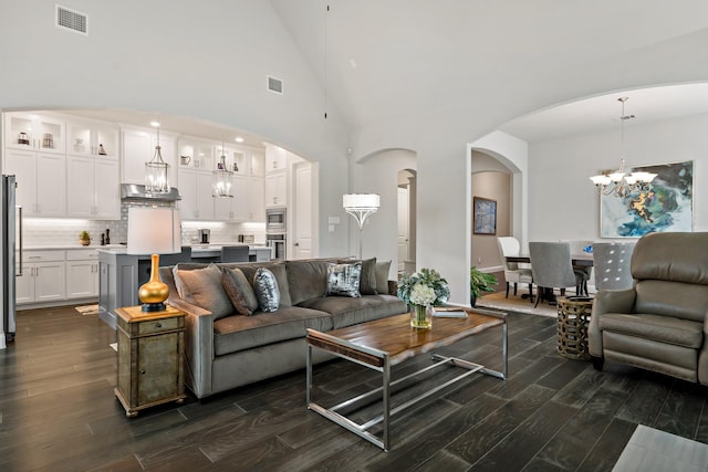 living room with a notable chandelier, dark wood-type flooring, and high vaulted ceiling