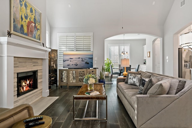 living room featuring a fireplace, dark wood-type flooring, lofted ceiling, and an inviting chandelier