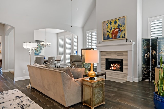 living room with a fireplace, dark wood-type flooring, high vaulted ceiling, and an inviting chandelier