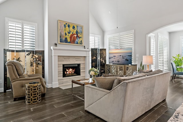 living room with high vaulted ceiling, dark wood-type flooring, and a tiled fireplace