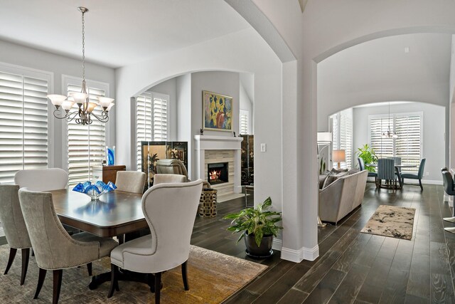 dining room featuring a wealth of natural light, a fireplace, dark hardwood / wood-style floors, and a notable chandelier