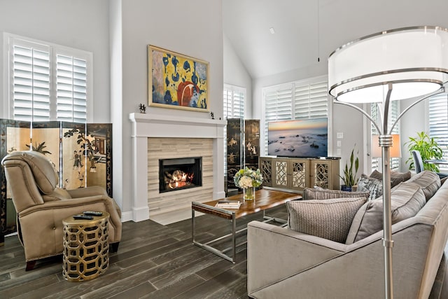 living room with a tile fireplace, dark wood-type flooring, and high vaulted ceiling