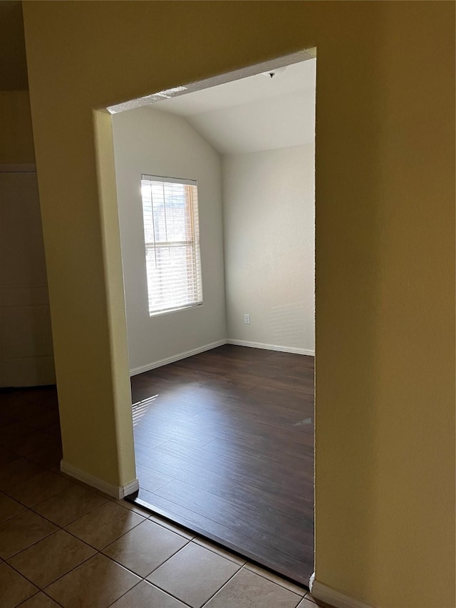 empty room featuring lofted ceiling and tile patterned floors