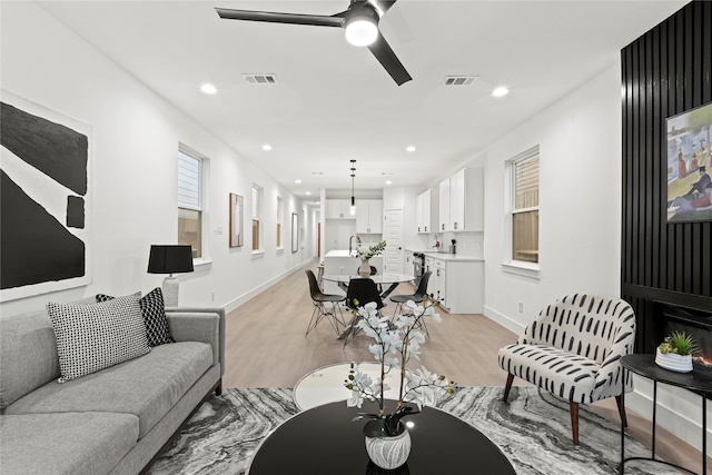 living room with ceiling fan, light wood-type flooring, and sink