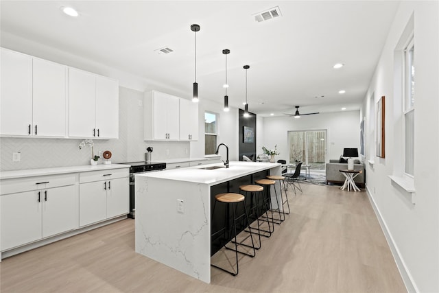 kitchen featuring white cabinetry, sink, an island with sink, and ceiling fan