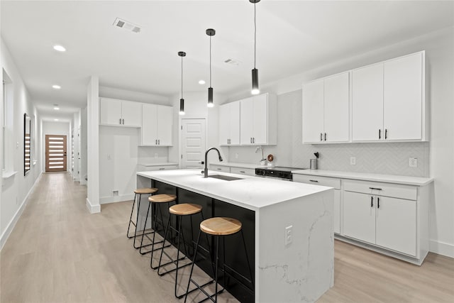 kitchen featuring white cabinetry, sink, a kitchen island with sink, and light hardwood / wood-style floors