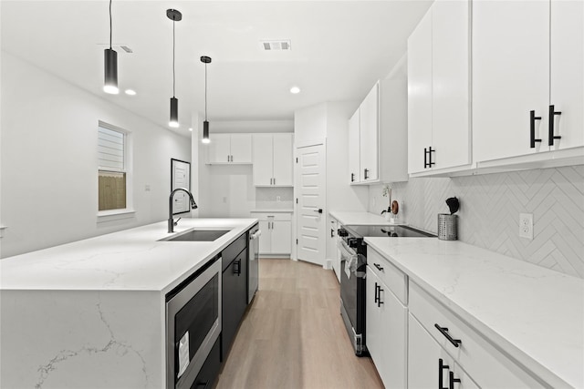 kitchen featuring stainless steel appliances, sink, decorative light fixtures, light hardwood / wood-style floors, and white cabinetry