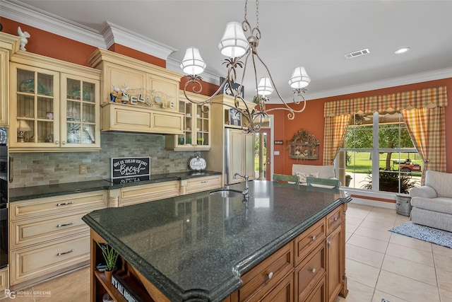 kitchen with pendant lighting, sink, ornamental molding, a center island with sink, and decorative backsplash