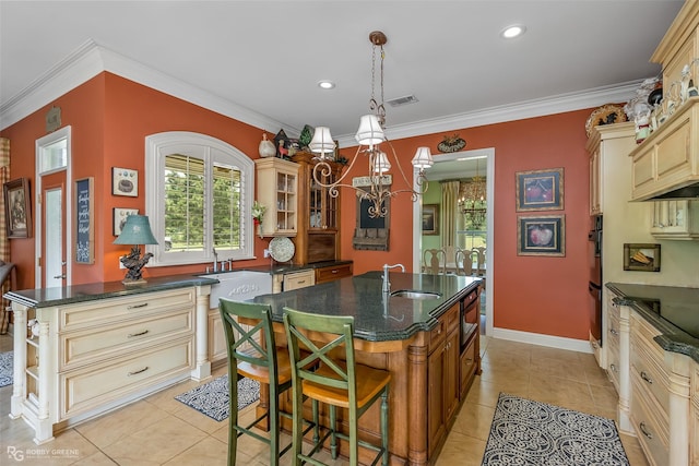 kitchen with pendant lighting, sink, crown molding, a breakfast bar, and a kitchen island with sink