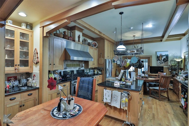 kitchen featuring sink, hanging light fixtures, light wood-type flooring, beam ceiling, and wall chimney range hood