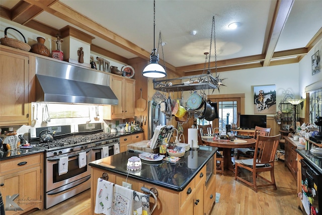 kitchen with range with two ovens, a kitchen island, wall chimney range hood, and light hardwood / wood-style floors