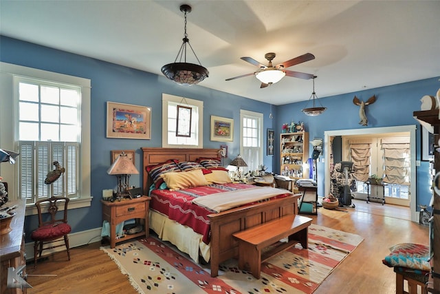 bedroom featuring ceiling fan, light wood-type flooring, baseboard heating, and multiple windows