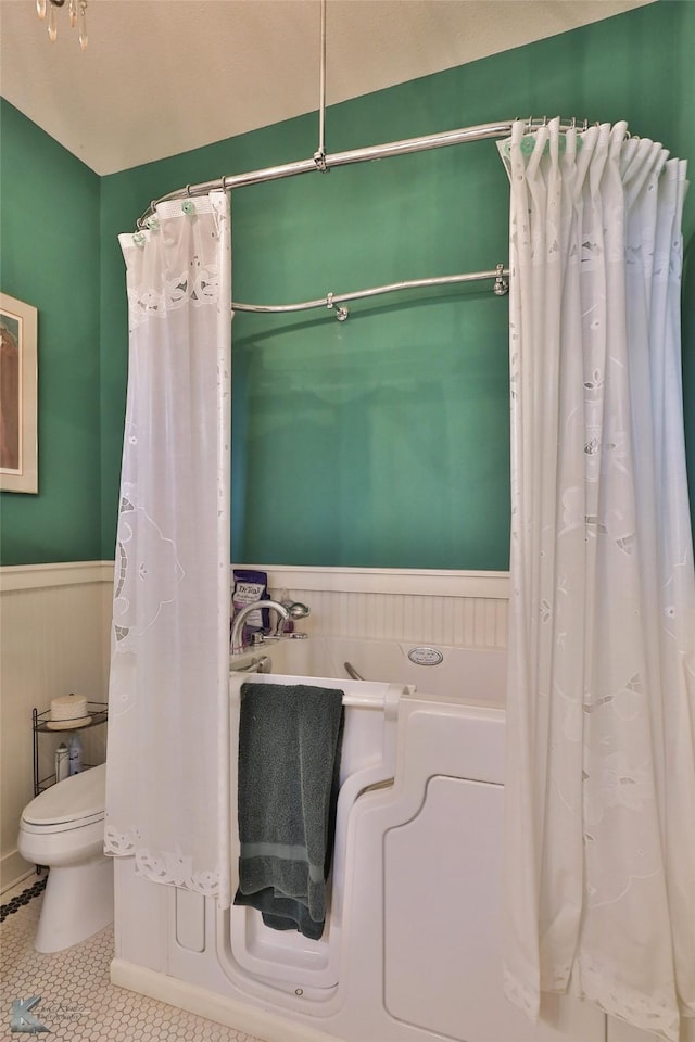 bathroom featuring tile patterned flooring, toilet, and a bathing tub