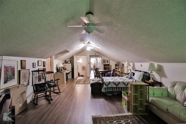 bedroom with ceiling fan, lofted ceiling, wood-type flooring, and a textured ceiling