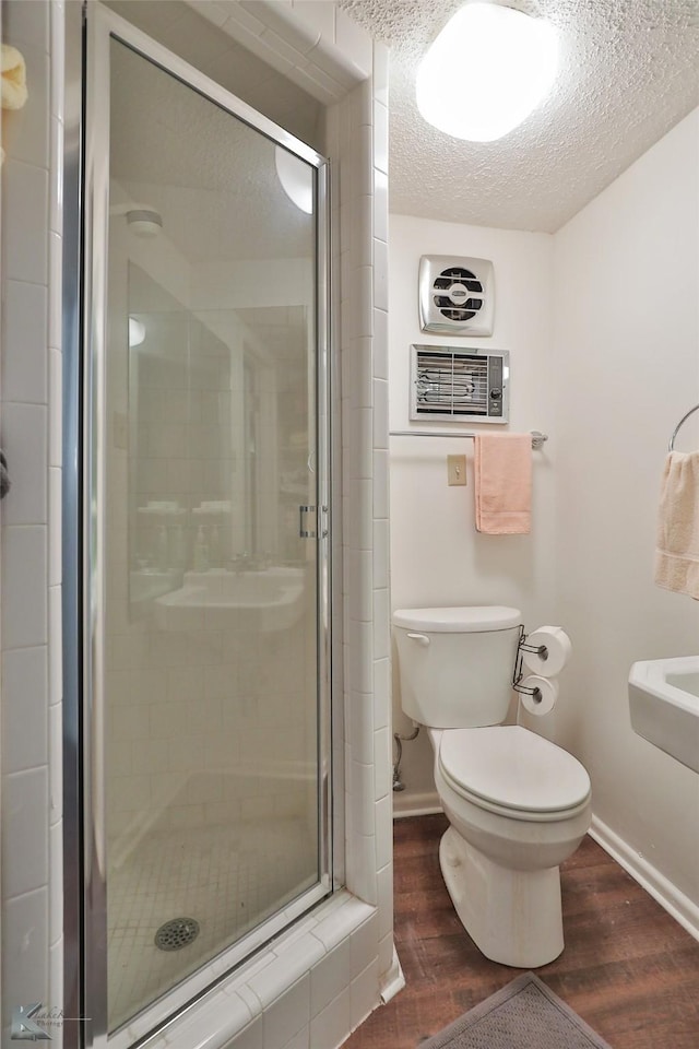 bathroom featuring toilet, an enclosed shower, wood-type flooring, and a textured ceiling