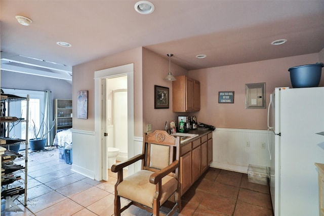 kitchen featuring white refrigerator, hanging light fixtures, sink, and light tile patterned floors