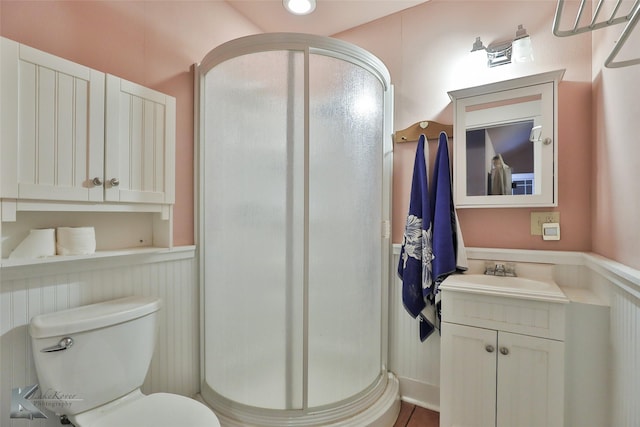 bathroom featuring vanity, toilet, and a shower with door