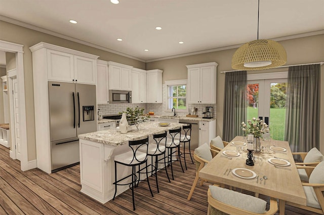 kitchen featuring appliances with stainless steel finishes, a center island, light hardwood / wood-style floors, white cabinetry, and hanging light fixtures