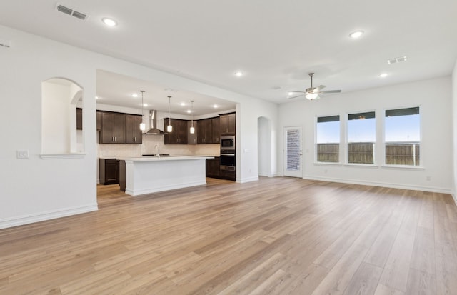 unfurnished living room with ceiling fan, sink, and light wood-type flooring