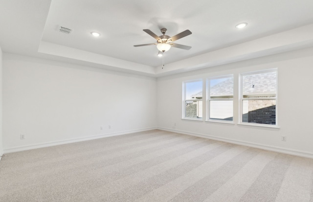 carpeted empty room featuring ceiling fan and a tray ceiling