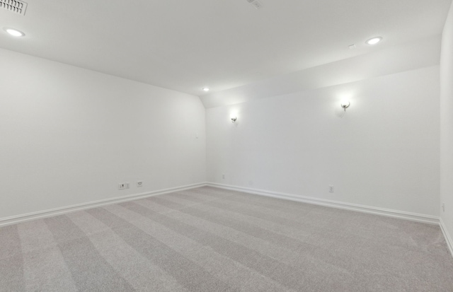 empty room featuring vaulted ceiling and light colored carpet