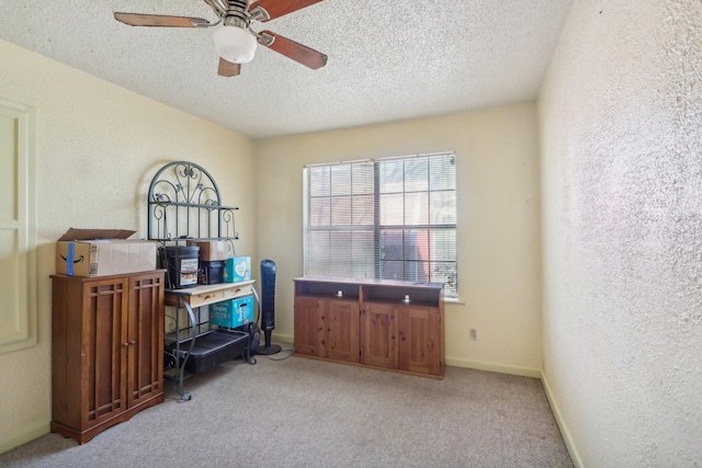 carpeted home office featuring ceiling fan and a textured ceiling