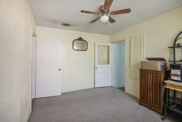 interior space with ceiling fan, carpet floors, and a textured ceiling