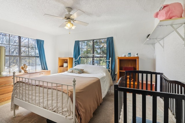 carpeted bedroom featuring ceiling fan, a textured ceiling, and multiple windows