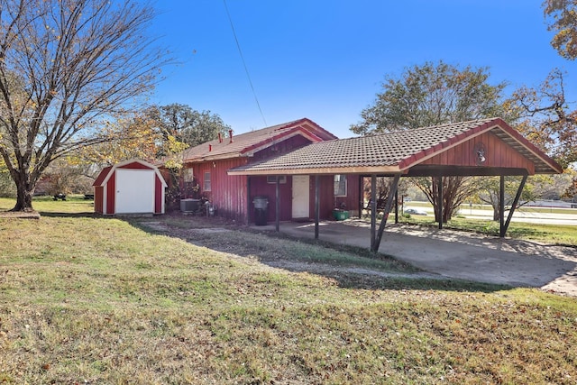 ranch-style home with a front yard, central AC unit, a carport, and a storage shed