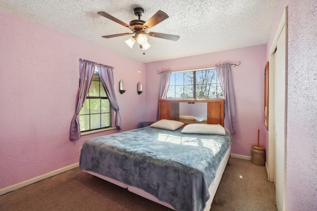 bedroom featuring ceiling fan, dark carpet, and a textured ceiling