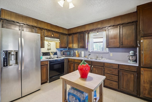 kitchen featuring dark brown cabinets, sink, a textured ceiling, and appliances with stainless steel finishes