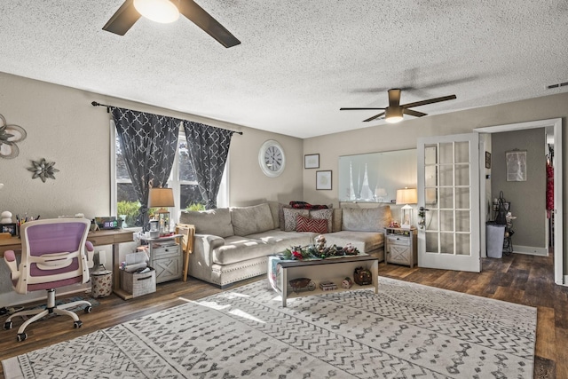 living room with ceiling fan, dark hardwood / wood-style flooring, and a textured ceiling