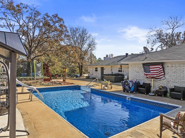 view of swimming pool with a trampoline, a patio area, a hot tub, and a water slide